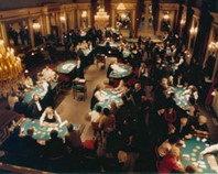 Vue d’en haut d’un casino bondé, où des groupes de clients élégamment vêtus jouent au poker.