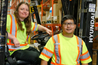 Two warehouse employees working on a forklift.