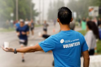 Volunteer holding out a cup of water during a marathon.